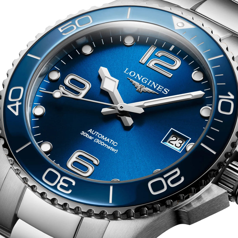 Close-up of a Longines HydroConquest wristwatch with a sunray blue dial, silver markers, date window, and stainless steel diving bezel (300m/30 bar), powered by the Calibre L888 automatic movement.