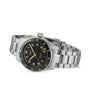 The Longines Spirit Zulu Time wristwatch features a stainless steel case, black dial with Arabic numerals, date window, green ceramic and black bezel, and metal link bracelet, displayed at an angle on a white background.