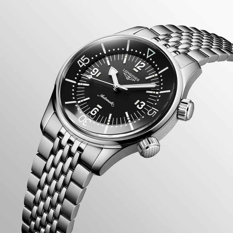 The Longines Legend Diver wristwatch, featuring automatic movement, a black dial with bold white numerals, dual crowns, and a stainless steel link bracelet, is shown at an angle against a plain background.