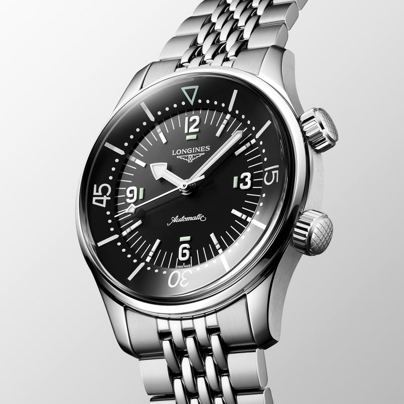 A Longines Legend Diver stainless steel automatic watch with a black dial and metal bracelet, shown angled on a light background.