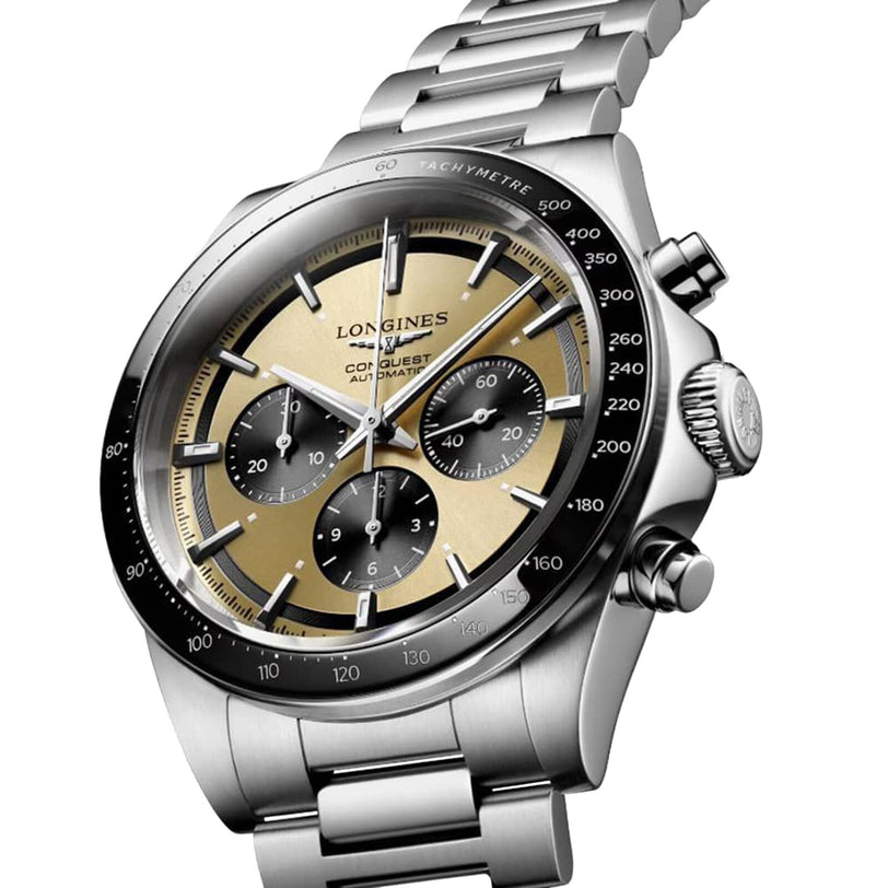 The Longines Conquest Chronograph is a stainless steel watch featuring a beige and black dial with three subdials, tachymeter bezel, and a metal bracelet—combining refined elegance and sporty performance.