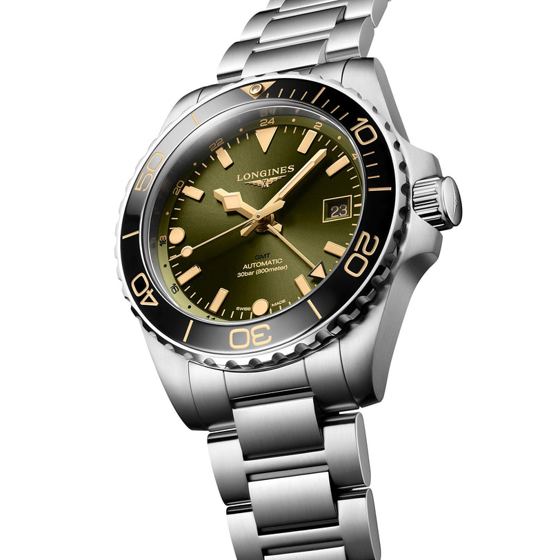 The Longines HydroConquest is a stainless steel diving watch featuring a green dial, black ceramic bezel, gold-tone hands and markers, date at 3 o’clock, and a metal bracelet.