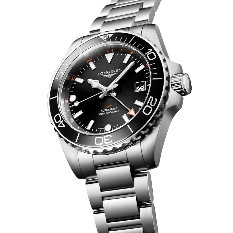 The Longines HydroConquest GMT, a stainless steel diving watch with black bezel and dial, orange GMT hand, date display, water resistance, and a silver bracelet is shown angled on a white background.
