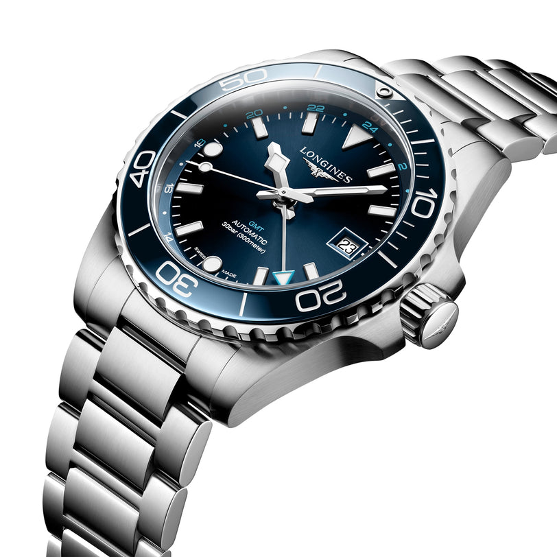 The Longines HydroConquest is a silver stainless steel diver’s watch with a blue dial, rotating bezel, date at 3 o’clock, and luminous hands and markers in a steel case, photographed at an angle on a white background.