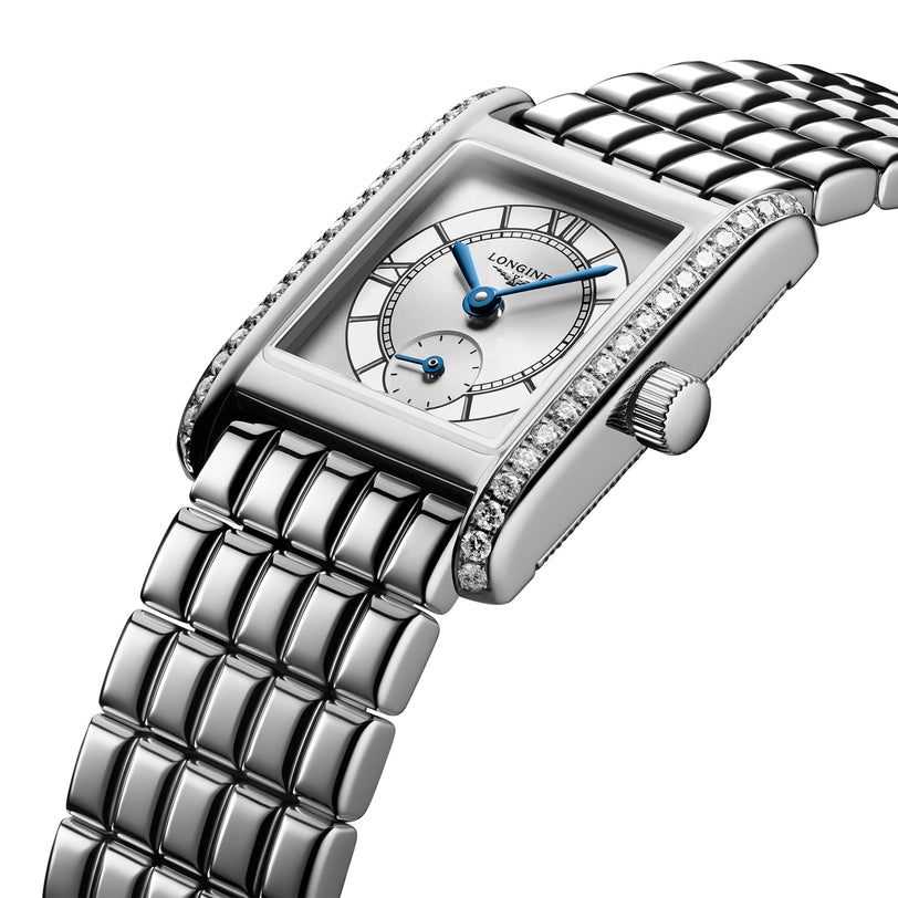 The Longines Mini DolceVita features a silver stainless steel bracelet, blue hands, small seconds subdial, and a bezel adorned with Top Wesselton diamonds.