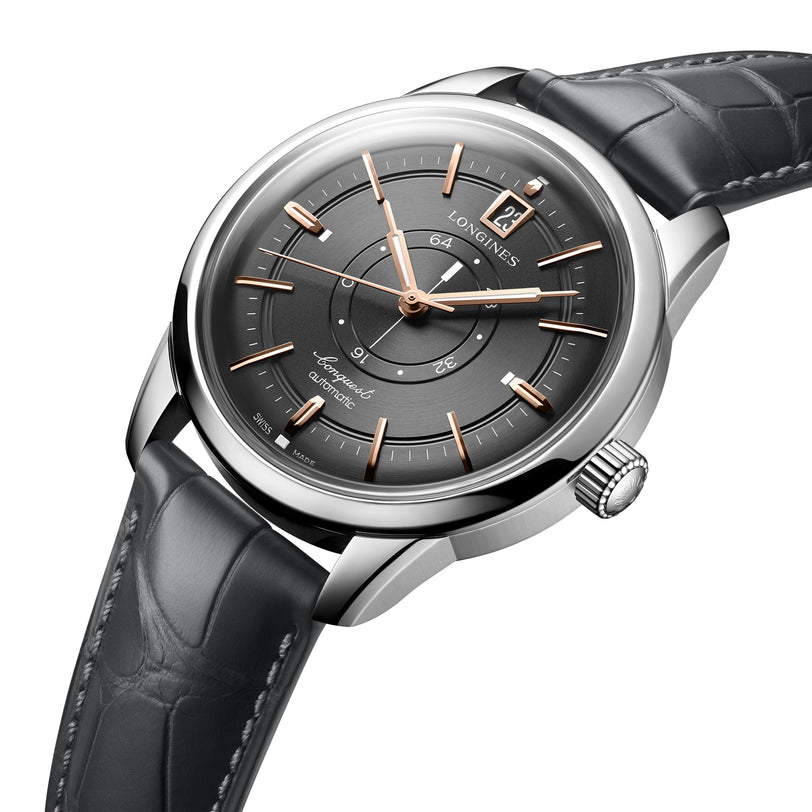 The Longines Conquest Heritage Central Power Reserve wristwatch features a silver and black design, dark grey leather strap, gold Swiss SuperLumiNova® hour markers, a date window at 12 o’clock, and Automatic on the dial.