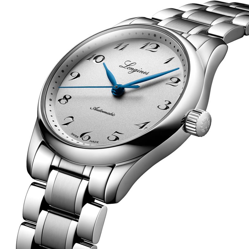 The Longines Master Collection features a silver analog wristwatch with a metal bracelet, blue hands, Arabic numerals, automatic movement, and Longines and Automatic on its white dial.