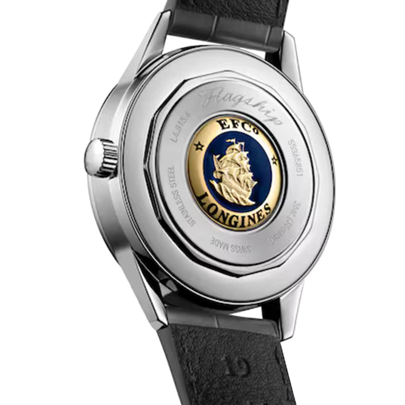 A close-up of the back of the Longines Flagship Heritage Moonphase watch, showcasing an engraved ship emblem at the center and a black leather strap.