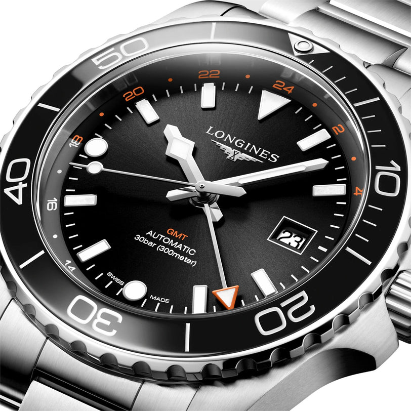 Close-up of a Longines Hydroconquest automatic watch featuring a black dial and bezel, orange GMT hand, date window, stainless steel case, and 300m water resistance.