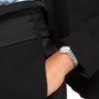 A person in a black suit and light blue shirt has their hand in their pocket, highlighting the timeless elegance of the Longines La Grande Classique de LONGINES silver wristwatch.