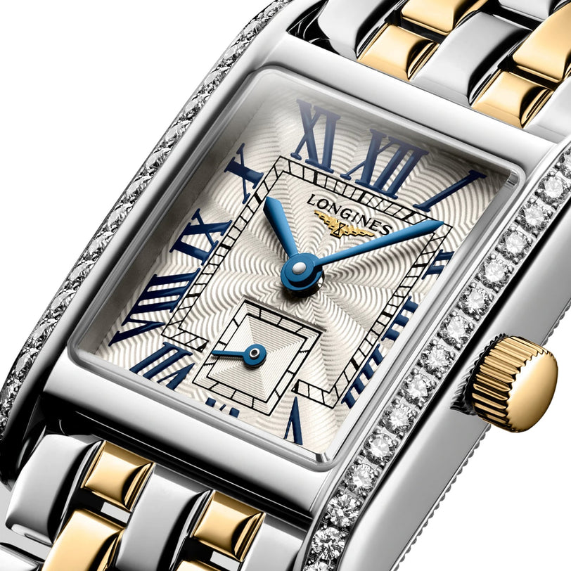 Close-up of the Longines Mini DolceVita wristwatch, showcasing a silver and gold bracelet, blue Roman numeral markers, and diamond-accented bezel for a touch of contemporary elegance.