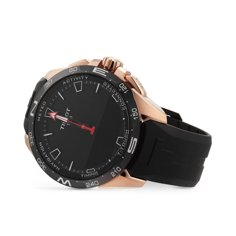 The Tissot T-Touch Connect Solar wristwatch features a black and rose gold design, black rubber strap, round face with marked bezel, and solar-powered functionality. Shown resting on its side.