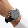 A person wears a Tissot T-Touch Connect Solar wristwatch with a black rubber strap, antimagnetic titanium case, and solar power reserve, paired with a white cuffed shirt.