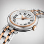 The Tissot Bellissima Small features a silver and rose gold PVD band, white dial with black Roman numerals, Swiss quartz movement, and a date window at 6 o’clock.