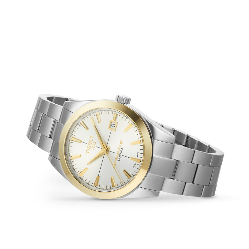 The Tissot Gentleman Powermatic 80 Silicium features a silver and gold metal bracelet, solid 18K gold bezel, white dial with date at 3 o’clock, and silver hour markers—an elegant display of Tissot’s craftsmanship on a white background.
