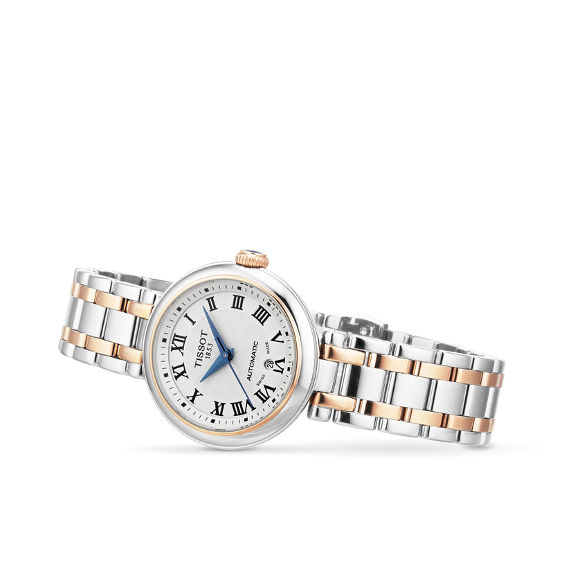The Tissot Bellissima Automatic features a silver and gold metal band, white dial, Roman numeral hour markers, and a gold crown, embodying the luxury and elegance Tissot is known for.