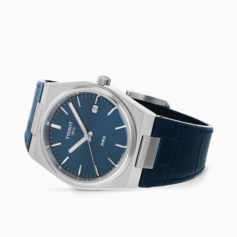 The Tissot PRX watch features a blue dial, silver hour markers, date display, and a blue leather strap. It is shown at an angle on a white background.