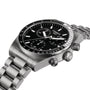 The Tissot PR516 Chronograph, featuring a black dial with silver indices, a stainless steel case, tachymeter bezel, and metal bracelet, is displayed at an angle.