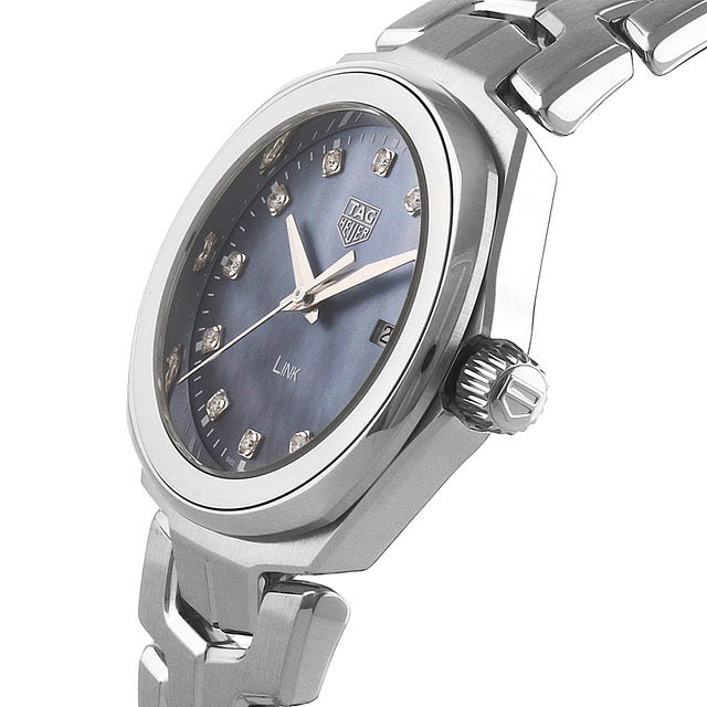 A silver TAG Heuer Link Date ladies watch with a dark blue dial, diamond hour markers, and a date window, shown at an angle.