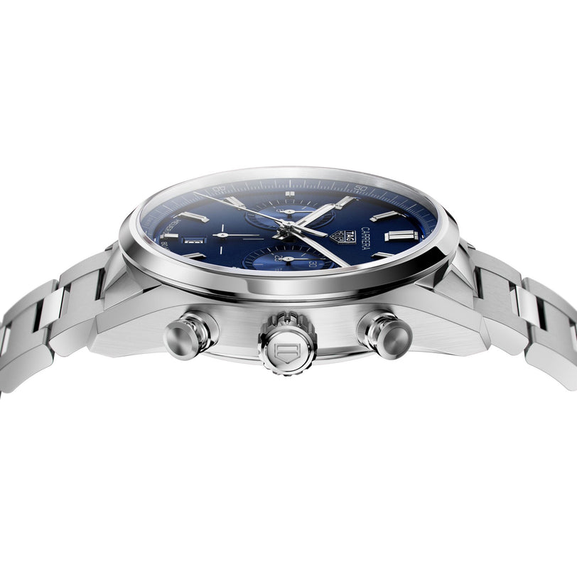 The TAG Heuer Carrera Chronograph features a stainless steel case, blue dial with chronograph subdials, and metal bracelet—shown in profile to highlight the crown and pushers that evoke its motor-racing heritage.