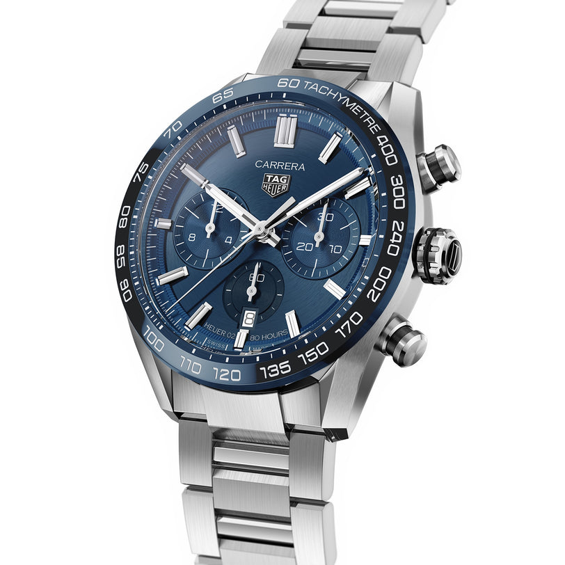 The TAG Heuer Carrera Chronograph features a stainless steel case, blue dial, automatic movement, three subdials, tachymeter bezel, and a matching metal bracelet, displayed at an angle.