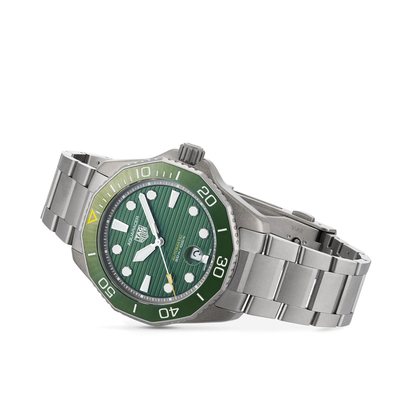 The TAG Heuer Aquaracer Professional 300 Date is a silver stainless steel sports watch featuring a green dial and bezel, white markers, date window, and metal link bracelet.