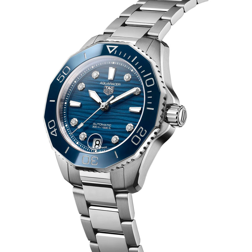 The TAG Heuer Aquaracer Professional 300 Date dive watch features a stainless steel case, blue bezel, blue dial with diamond markers, date at 6 o’clock, and a classic metal bracelet.
