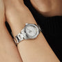 A TAG Heuer Aquaracer Professional 200 with a stainless steel case, white dial, and metal band is worn on a persons wrist, seen against a black sleeve.