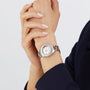 A person in a dark sleeve holds their wrist with the other hand, wearing a TAG Heuer Aquaracer Professional 200 featuring a round face and stainless steel case.