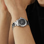 A TAG Heuer Aquaracer Professional 200 Date with a black mother-of-pearl dial and silver accents is worn on a person’s left wrist.