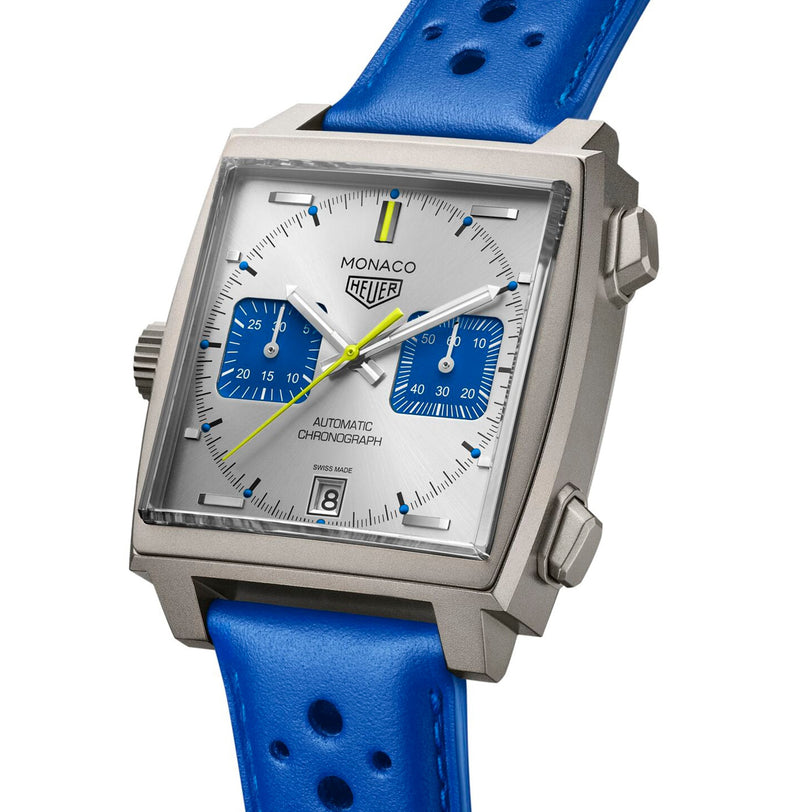 The Limited Edition Monaco Chronograph French Racing Blue by TAG Heuer features a square silver case, white dial with blue subdials, yellow second hand, perforated blue leather strap, and is powered by the Calibre 11 automatic movement.