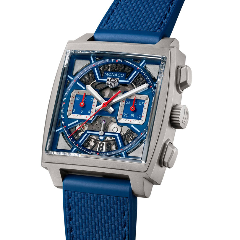 The TAG Heuer Monaco Chronograph features a square silver case, blue skeletonised dial with Heuer 02 movement, red and blue subdials, date display, and a blue textured strap.