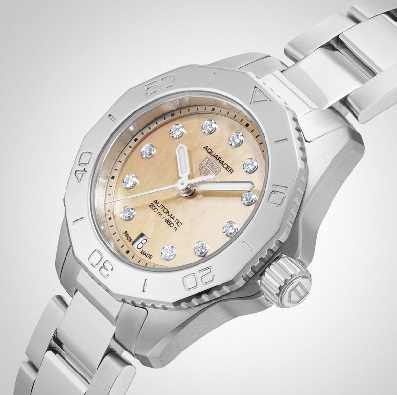 A TAG Heuer Aquaracer Professional 200 Date wristwatch with Calibre 9 Automatic Movement, cream dial, diamond hour markers, and a metal band is shown against a light background.