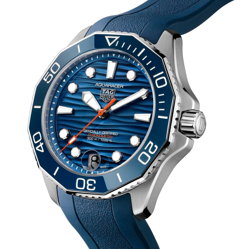 The TAG Heuer Aquaracer Professional 300 Date is a luxury chronograph with a stainless steel case, blue bezel, and blue rubber strap, showcased in a close-up angled view inspired by deep-sea exploration.