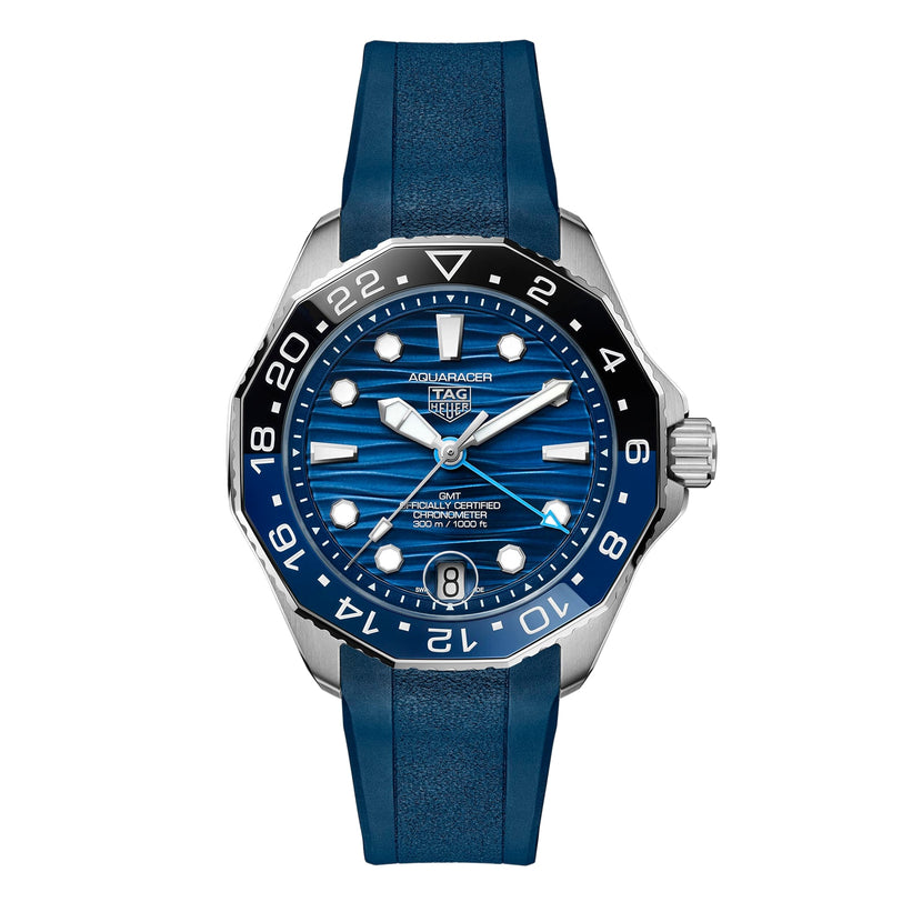 The TAG Heuer Aquaracer Professional 300 GMT is a luxury stainless steel watch with automatic movement, blue wave-patterned dial, blue bezel, rubber strap, date display, and GMT markings.