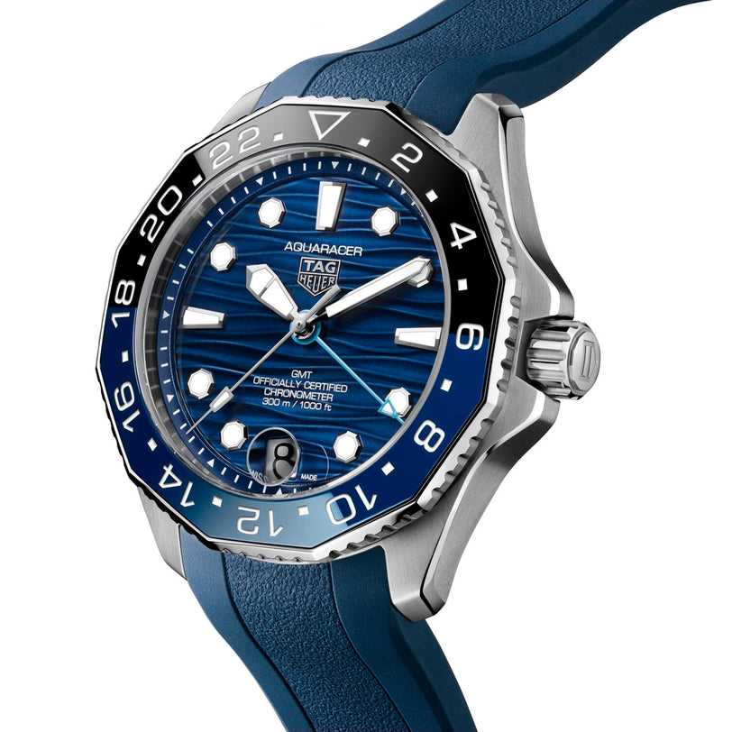 The TAG Heuer Aquaracer Professional 300 GMT is a luxury watch with a blue dial, blue and black bezel, blue rubber strap, and automatic movement, displaying the time at 10:10.