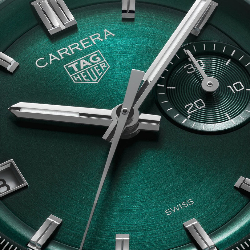 Close-up of a green TAG Heuer Carrera Chronograph watch face, inspired by the Carrera Panamericana race. Silver hour markers and a seconds subdial accentuate its elegant automatic movement, with the time set at 1:42:36.