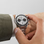 Someone wears a TAG Heuer Carrera Chronograph watch in silver and adjusts its crown.