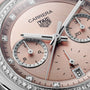 Close-up of a pink TAG Heuer Carrera Chronograph watch face featuring diamond accents and silver hands.
