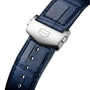 Close-up of a blue leather strap with a silver clasp, featuring the engraved shield logo of TAG Heuer on the Carrera Chronograph.