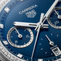 Close-up of the TAG Heuer Carrera Chronograph watch face in blue, featuring silver hands, subdials, and diamond hour markers.