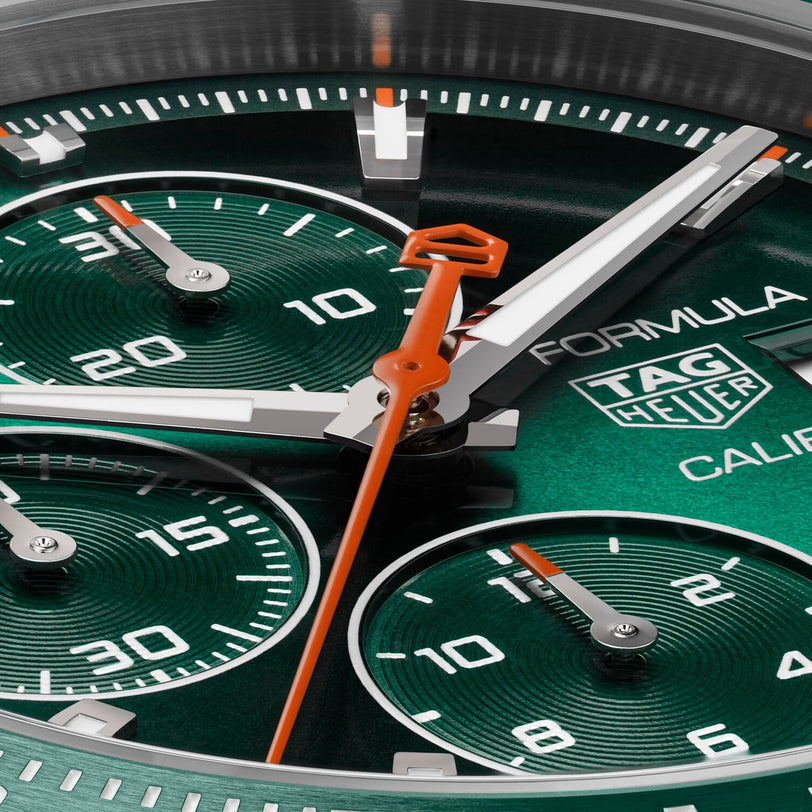 Close-up of a TAG Heuer Formula 1 Chronograph watch face showcasing green color, subdials, orange hands, prominent branding, and a striking green ceramic tachymeter bezel.