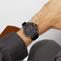A person wears a TAG Heuer Formula 1 Chronograph watch with a black band and red accents on their left wrist, reflecting the bold motorsport legacy of this iconic timepiece.