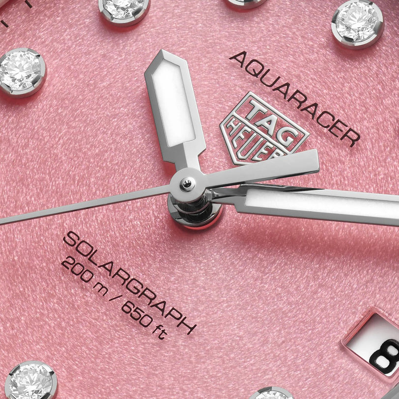 Close-up of a pink TAG Heuer Professional 200 Solargraph watch face with diamond markers and silver hands.