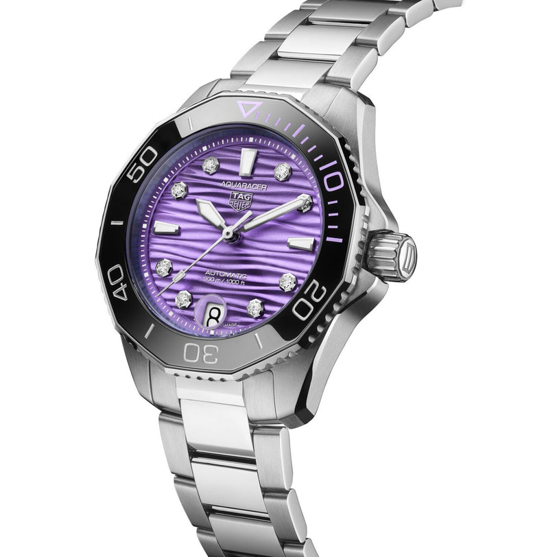 The TAG Heuer L SS AU BW AQUAR 300 36 PURP DD DL 25 is a silver wristwatch with a metallic band and a purple textured dial adorned with diamond hour markers.