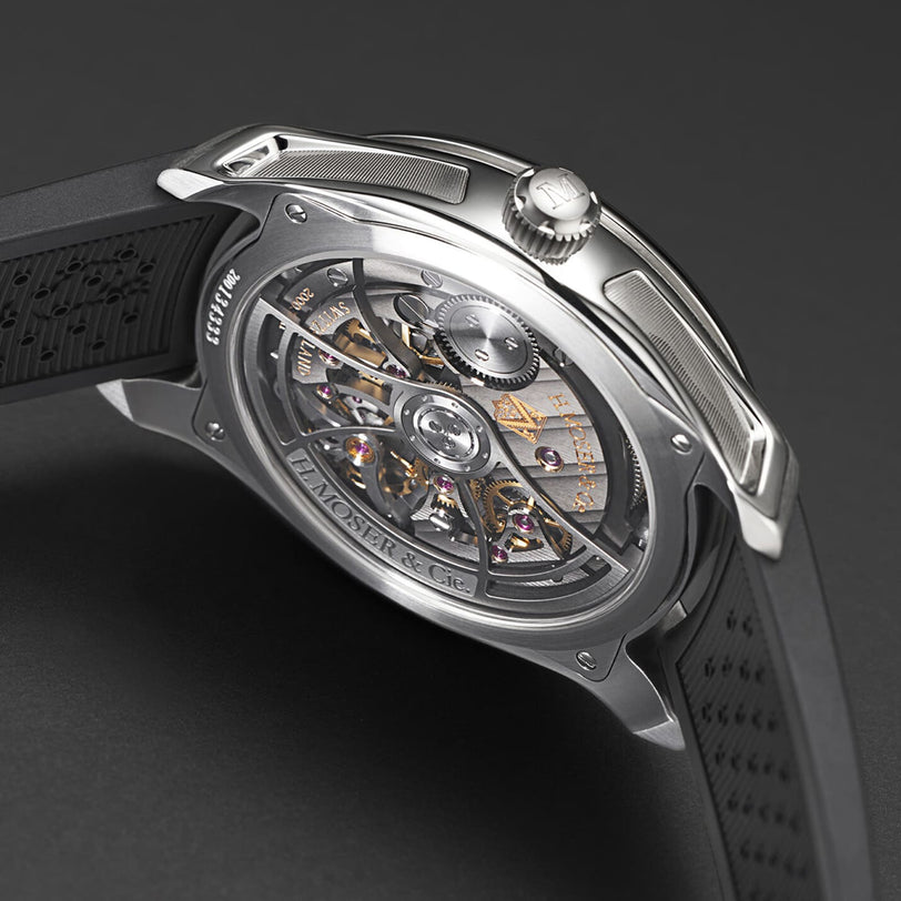 The H. Moser & Cie Pioneer Centre Seconds Cosmic Green is a luxury wristwatch with a transparent back revealing its intricate mechanical movement, paired with a black rubber strap.