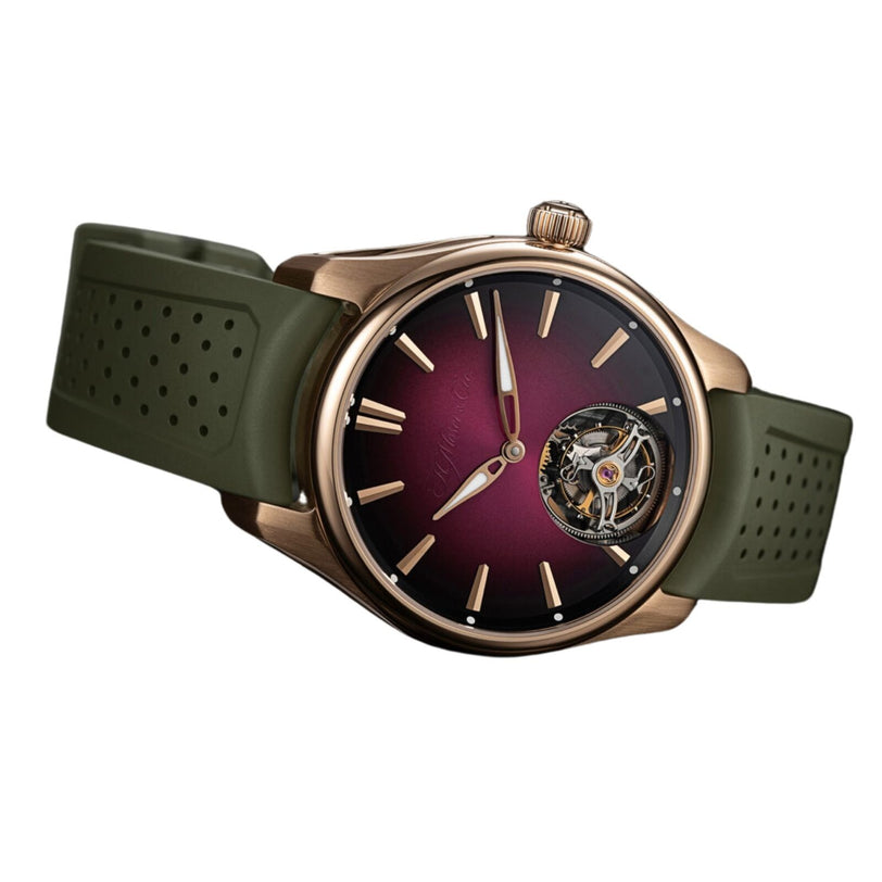 The H. Moser & Cie Pioneer Tourbillon Burgundy features a burgundy dial, gold case, green strap, and a visible tourbillon at 6 o’clock.