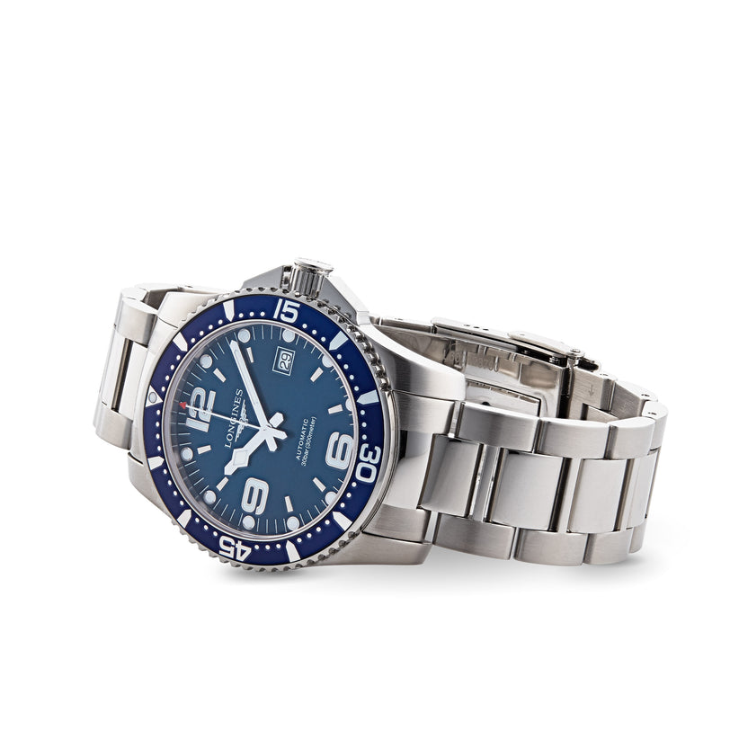 The Longines HydroConquest is a stainless steel diving watch featuring a blue dial, silver hour markers, date display, and metal link bracelet. Stylish and water resistant, it suits everyday wear and aquatic adventures. Shown on a white background.