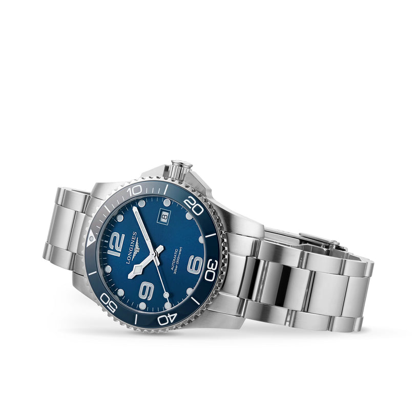 The Longines HydroConquest, a stainless steel diving watch with a blue dial, silver indices, and a rotating bezel, is shown at an angle on a white background.