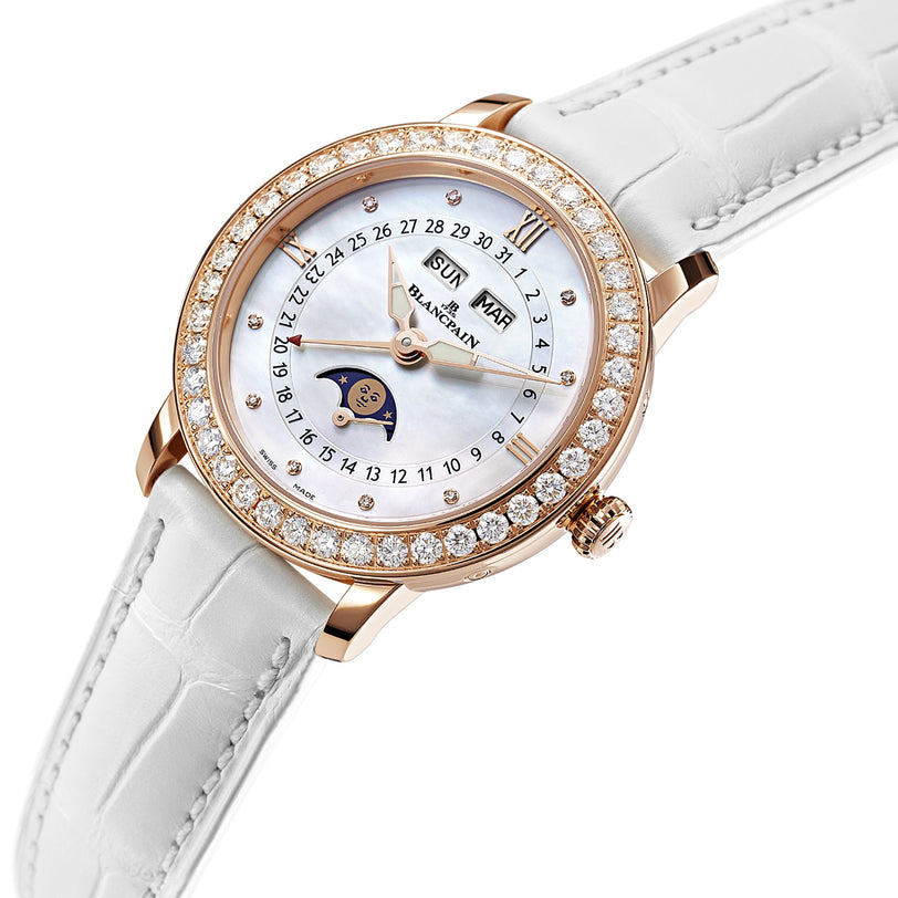 The Blancpain Ladybird Quantième Complet is a luxury wristwatch featuring a white leather strap, diamond bezel, moon phase and complete calendar on a mother-of-pearl dial—an elegant example of automatic movement.